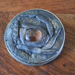 Close-up van een blauw-grijs decoratief object met spiraalpatroon en een rond gat in het midden