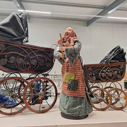 Vintage kinderwagens en poppen tentoongesteld in de winkel, waaronder een pop in traditionele kledij