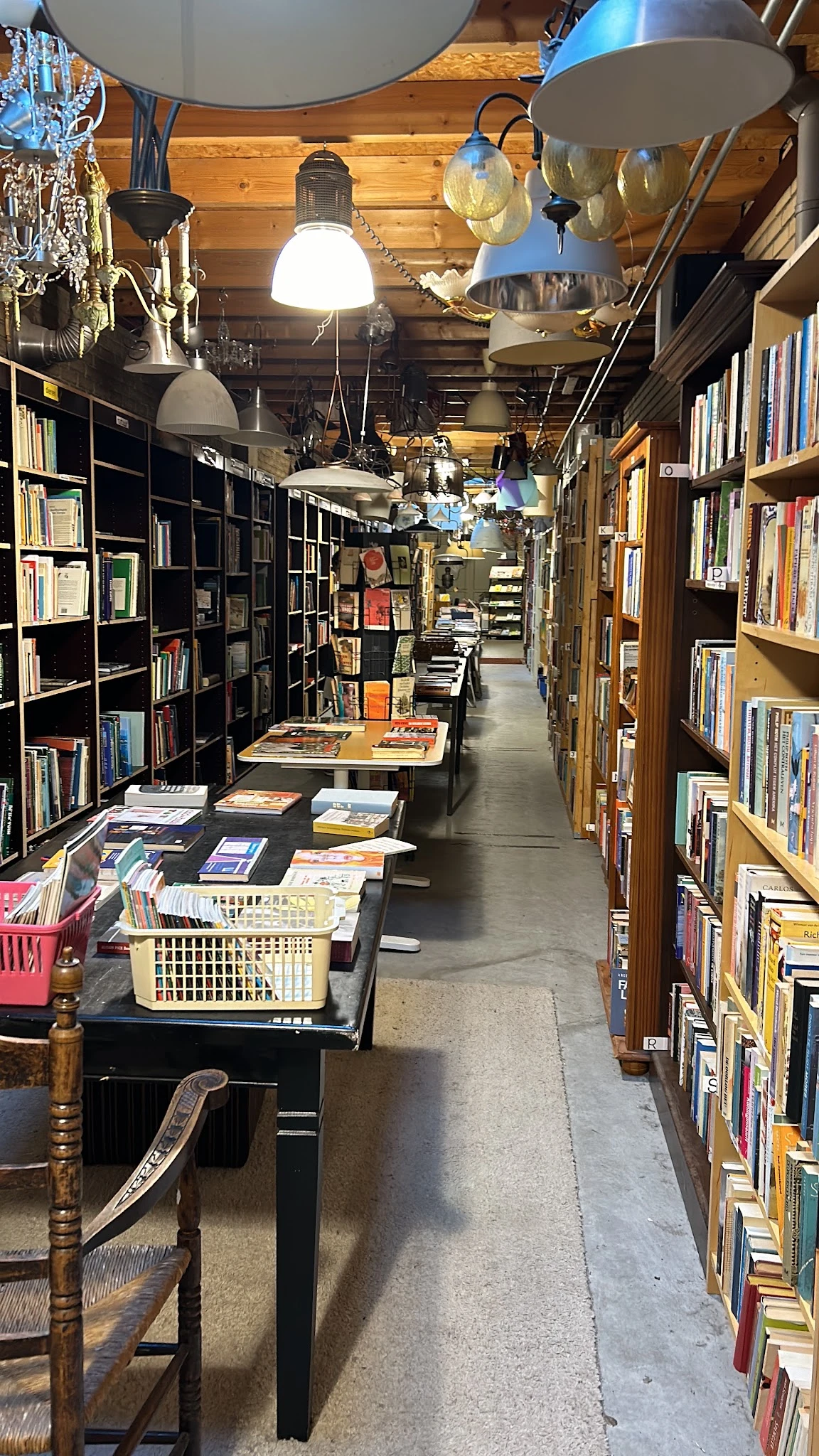 Winkelgangetje met boekenrekken aan beide zijden en manden met boeken op de grond