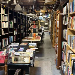 Winkelgangetje met boekenrekken aan beide zijden en manden met boeken op de grond