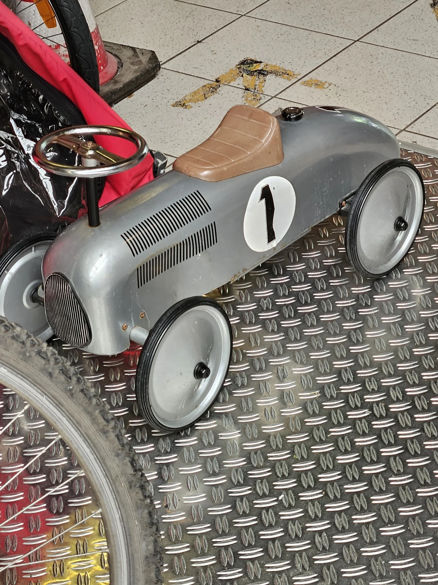 Zilveren vintage speelgoedracewagen met nummer 1 op metallic ondergrond