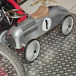 Zilveren vintage speelgoedracewagen met nummer 1 op metallic ondergrond