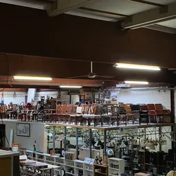Bovenkant van winkelinterieur met fluorescente verlichting en veel houten stoelen en meubels uitgestald