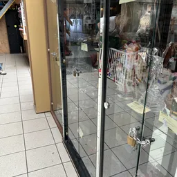 Glazen deur met zwarte frame in een kringloopwinkel, achter zichtbaar stellingen met kleding en spullen