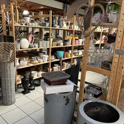 Wooden shelving units filled with decorative items, kitchenware, and miscellaneous goods in a thrift store