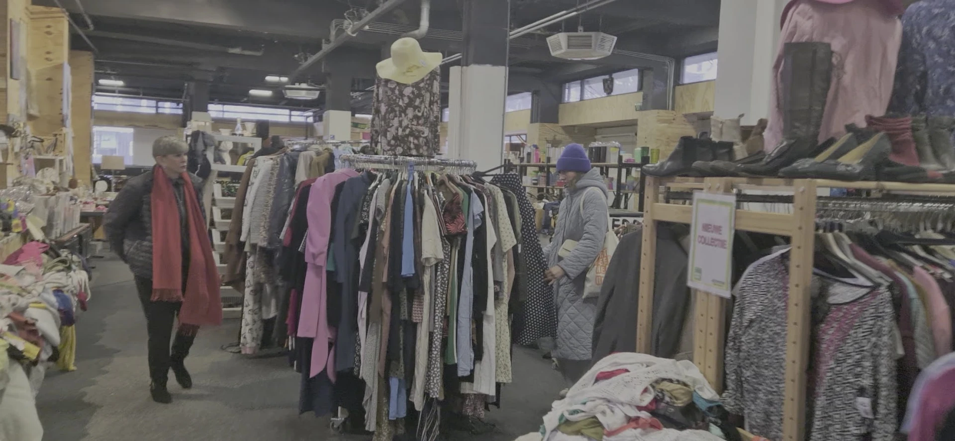 Rekken met tweedehands kleding, waaronder jurken en blouses in verschillende kleuren en patronen