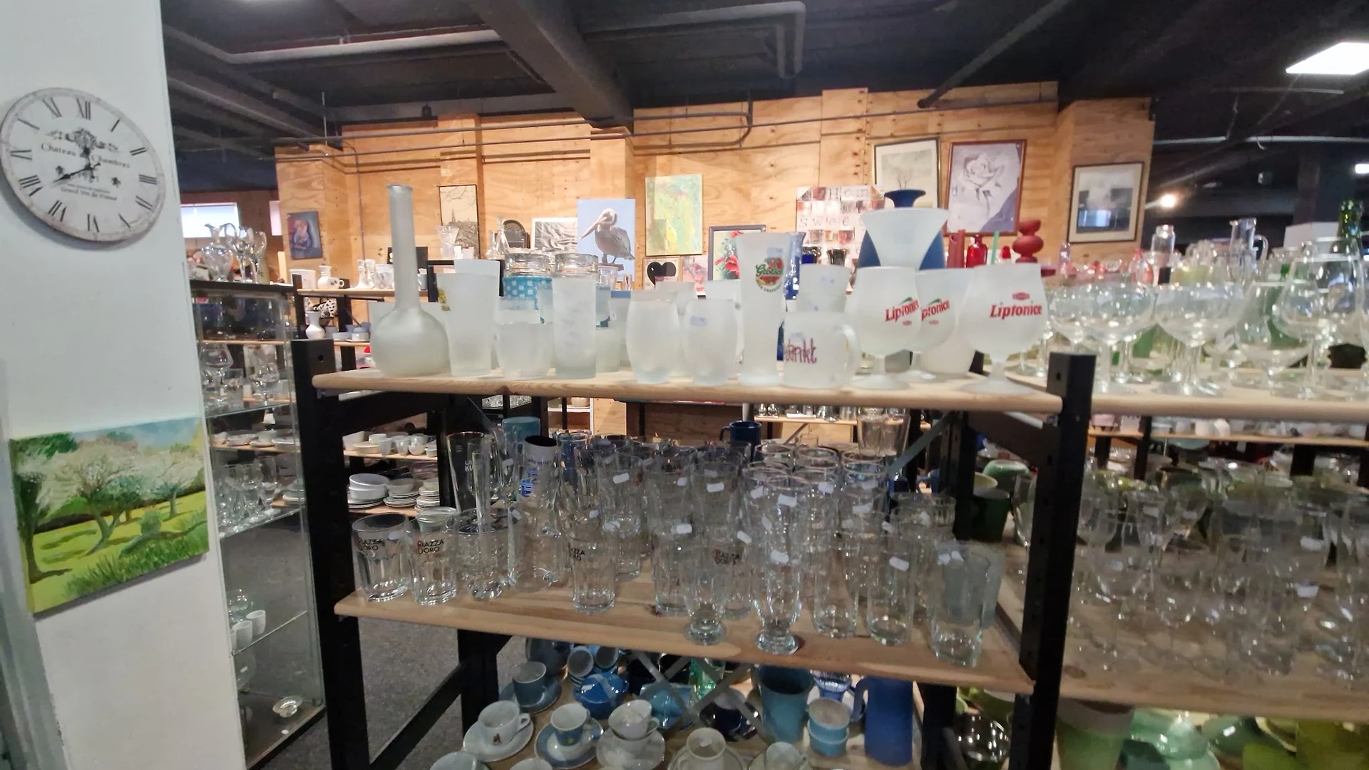 Stellingen met glazen bekers, flessen en servies in verschillende maten en kleuren