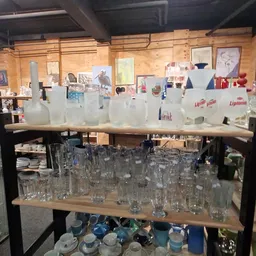 Stellingen met glazen bekers, flessen en servies in verschillende maten en kleuren