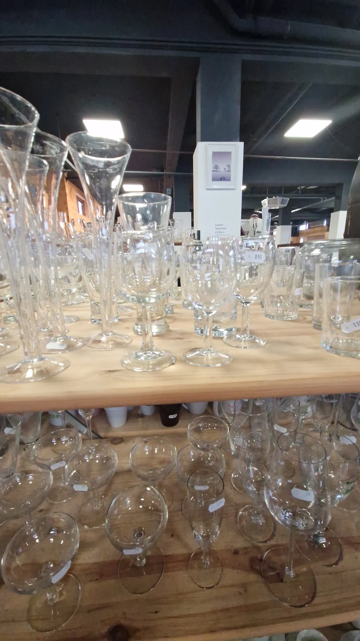 Glazen glazen met verschillende vormen en maten uitgestald op houten tafel in kringloopwinkel