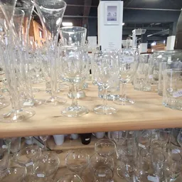Glazen glazen met verschillende vormen en maten uitgestald op houten tafel in kringloopwinkel