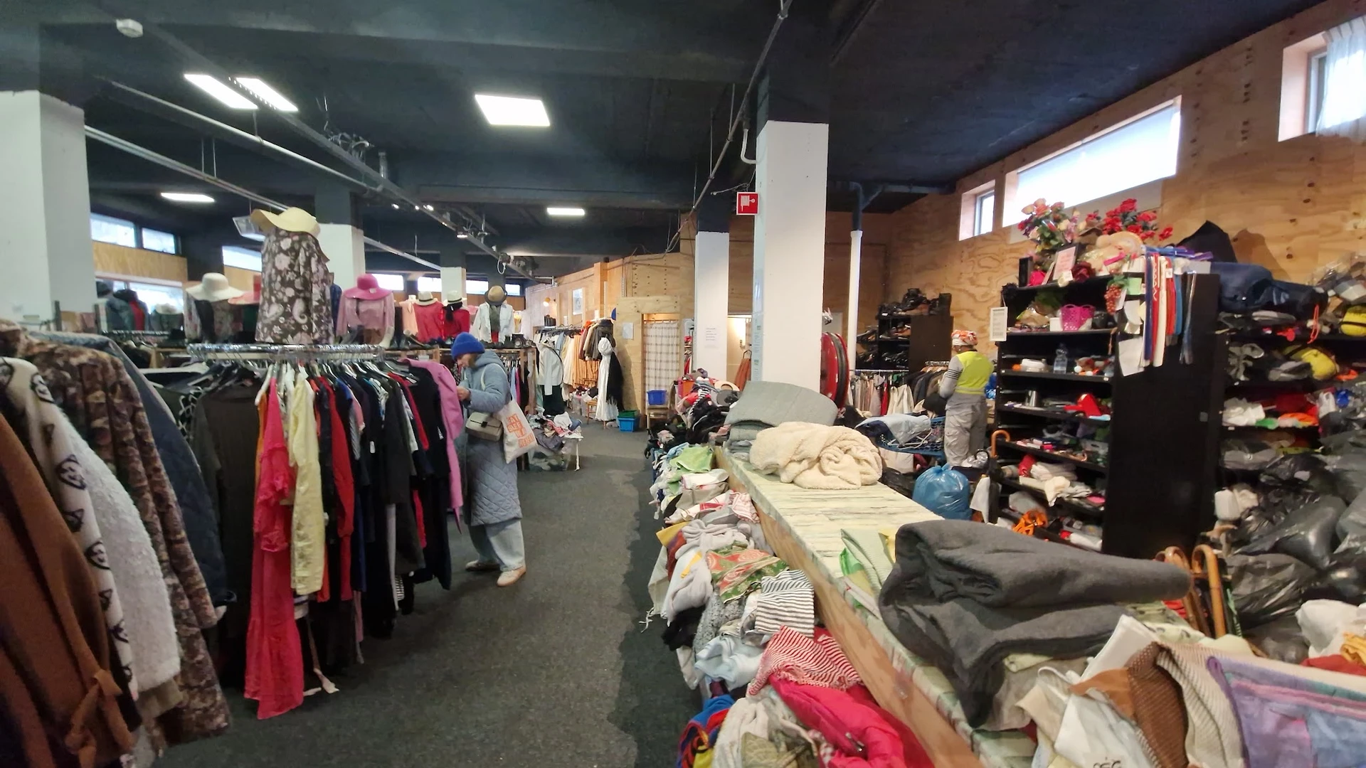 Winkelvloer met kledingrekken en tafels vol tweedehands kleding in een kringloopwinkel