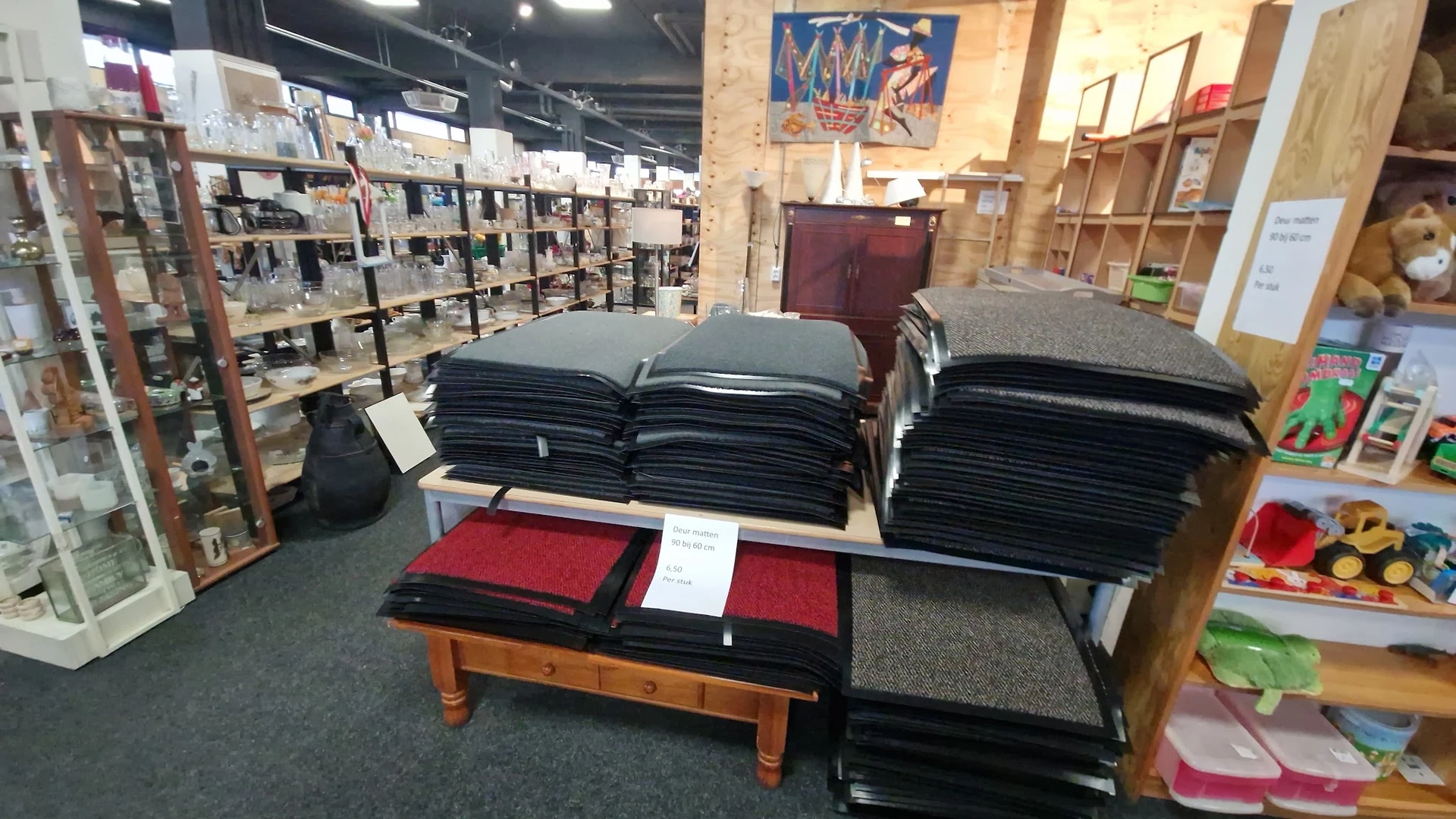 Uitgestalde stapels zwarte en rode textielwaren op een houten tafel in de winkel