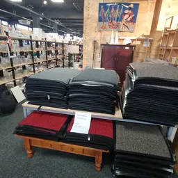 Uitgestalde stapels zwarte en rode textielwaren op een houten tafel in de winkel