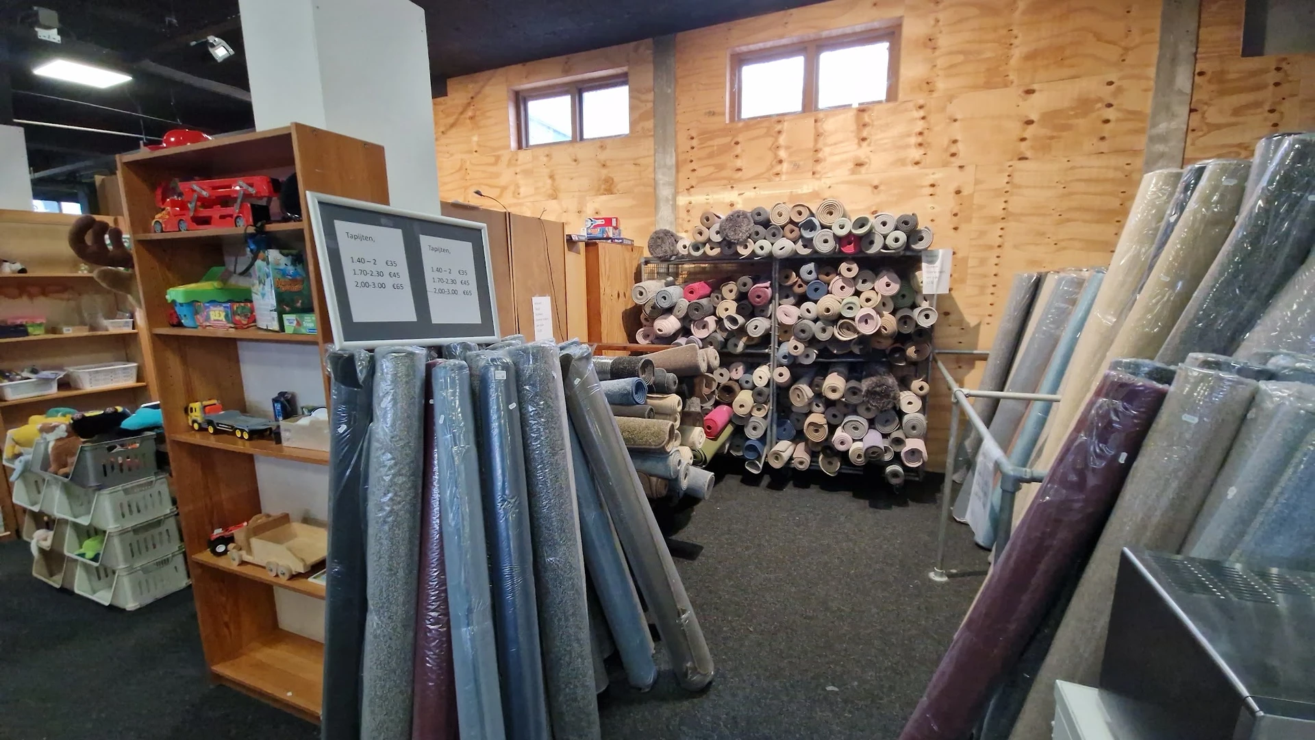 Uitgestalde stoffen en textiel op rollen en in rekken in een kringloopwinkel