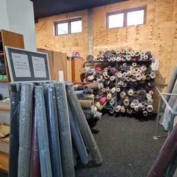 Uitgestalde stoffen en textiel op rollen en in rekken in een kringloopwinkel