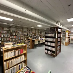 Binnenaanzicht van kringloopwinkel met boekenkasten, stellingen en tafels vol met boeken en media