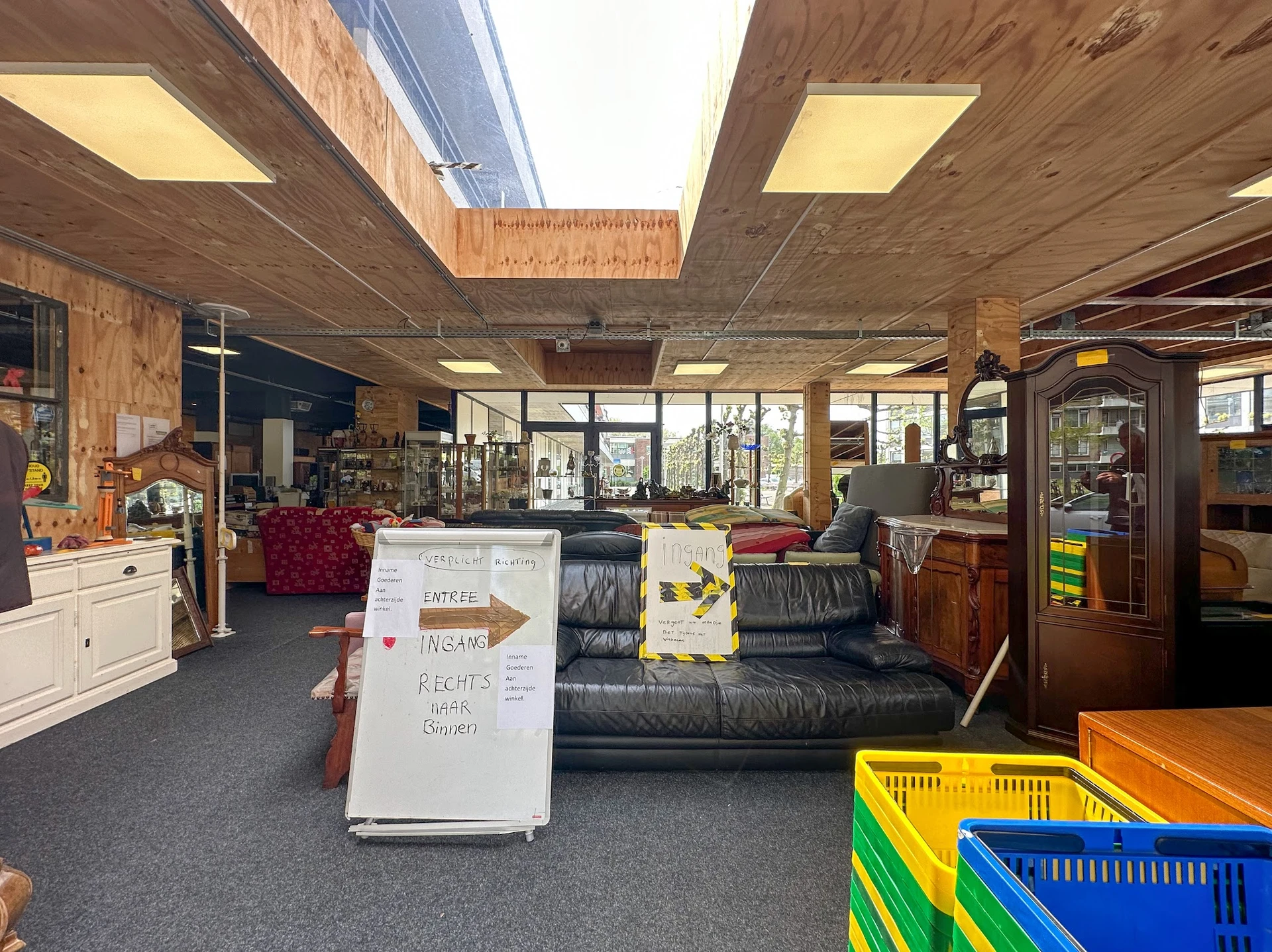 Winkelvloer van kringloopwinkel met zithoek, stellingen, gekleurde kratjes en informatiebord