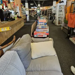 Winkelvloer met zitmeubels en gestapelde spullen in een kringloopwinkel