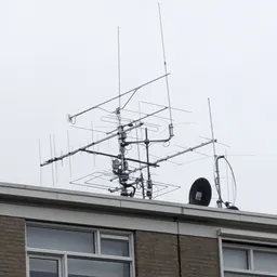 Antennes en schotels op het dak van een gebouw tegen grijze lucht