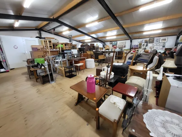 Winkelinterieur met diverse meubels, kasten, stoelen en huishoudelijke artikelen uitgestald op houten vloer