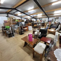 Winkelinterieur met diverse meubels, kasten, stoelen en huishoudelijke artikelen uitgestald op houten vloer