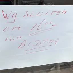 Handgeschreven notitie op wit papier met onleesbare tekst in rode inkt