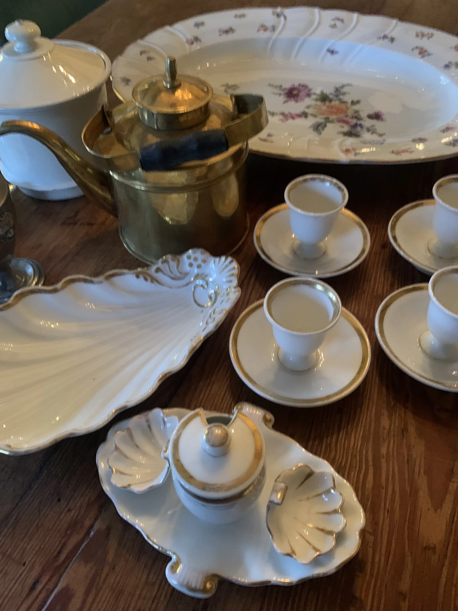 Witte porseleinen serviesset met gouden rand, bestaande uit schotels, kopjes en een decoratieve schaal