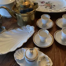 Witte porseleinen serviesset met gouden rand, bestaande uit schotels, kopjes en een decoratieve schaal