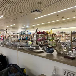 Uitstallingen met huishoudelijke artikelen, servies, decoratie en kitchenware op schappen en toonbank in kringloopwinkel