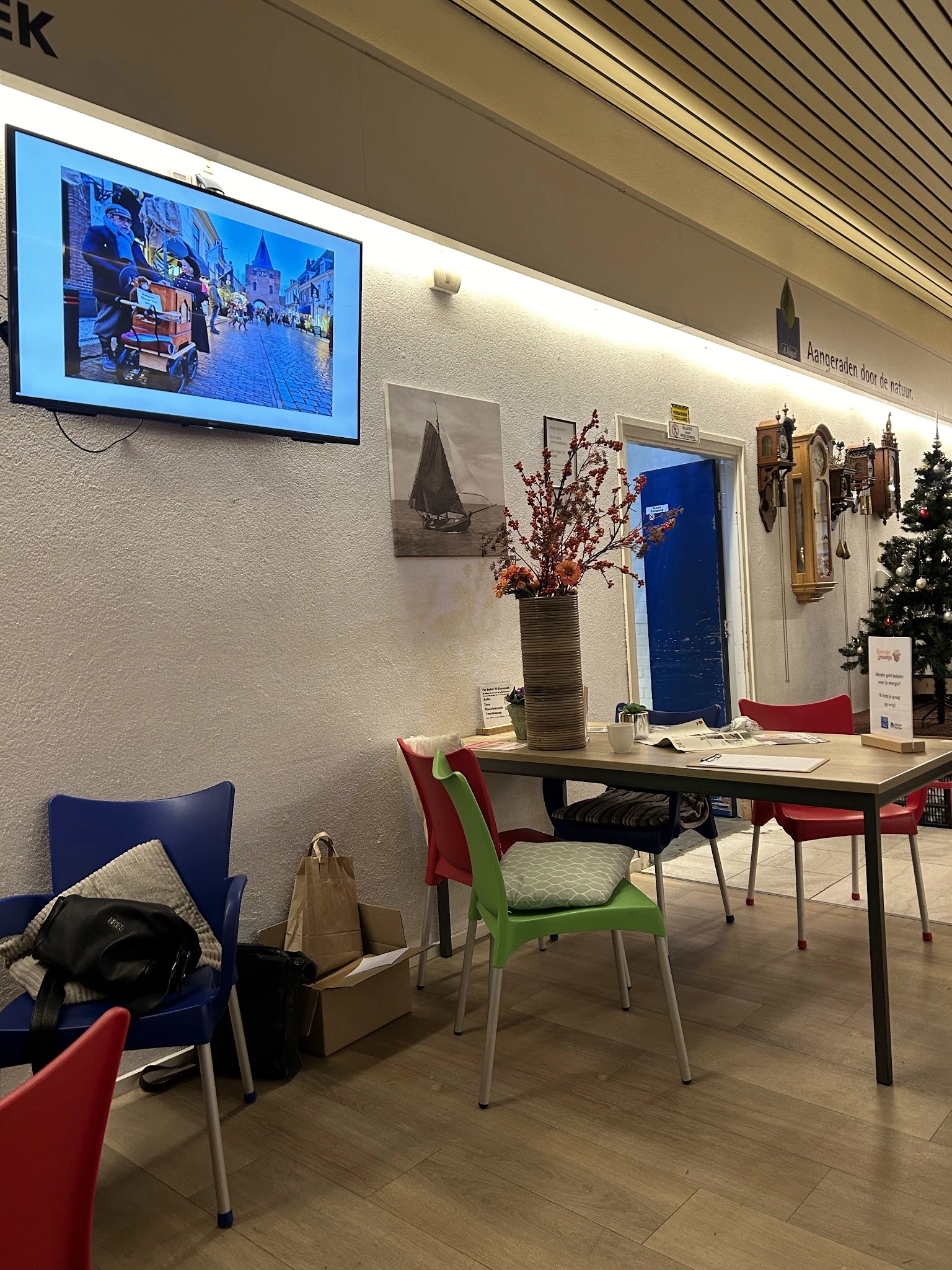 Winkelinterieur met tafel, gekleurde stoelen, bloemenvaas en decoraties aan de muur