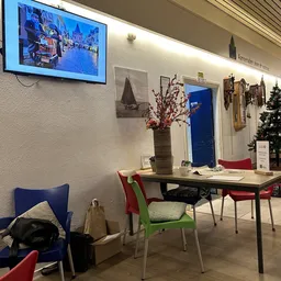 Winkelinterieur met tafel, gekleurde stoelen, bloemenvaas en decoraties aan de muur