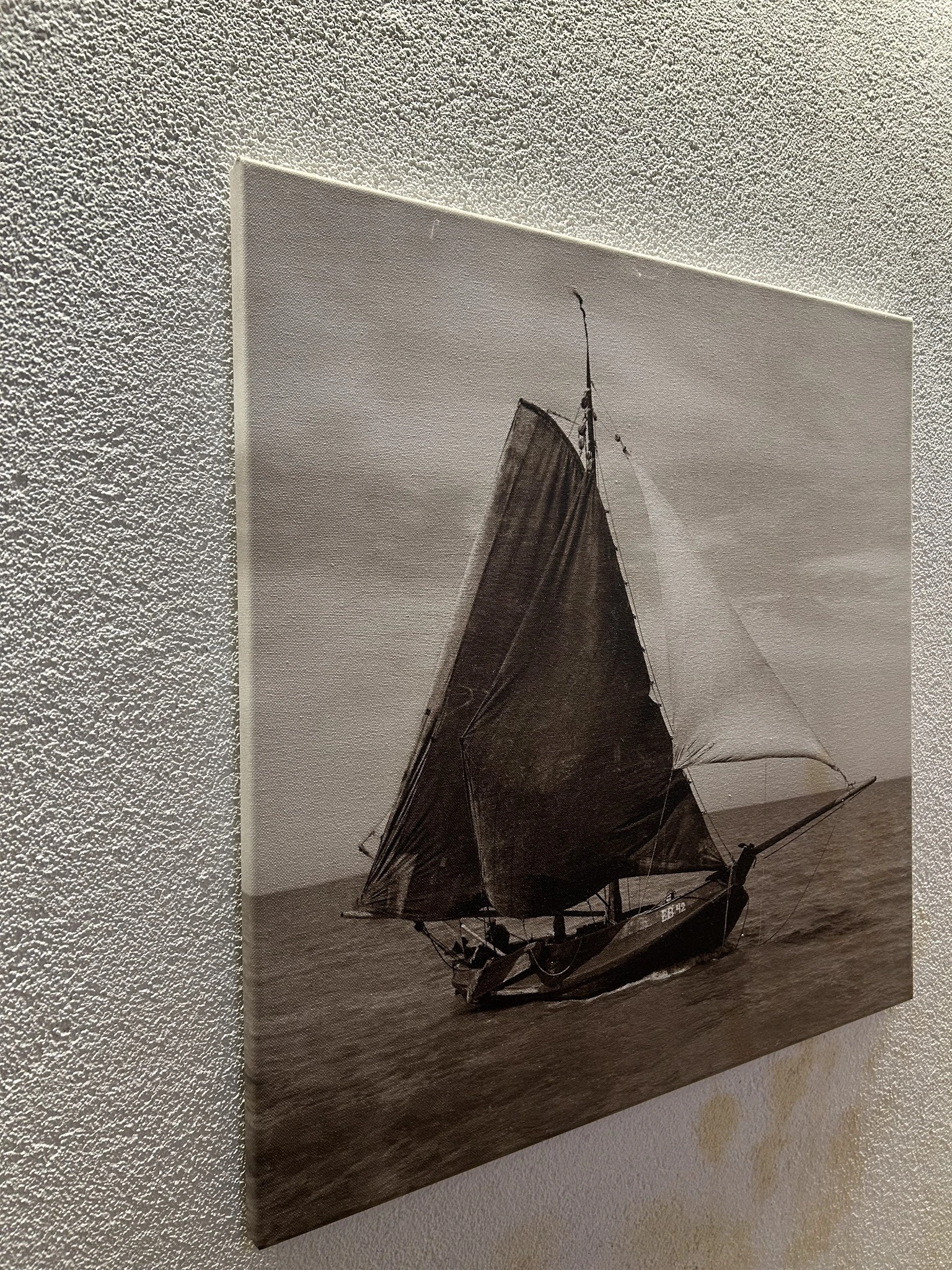 Sepia zwart-wit foto van een zeilboot met donkere zeil op zee