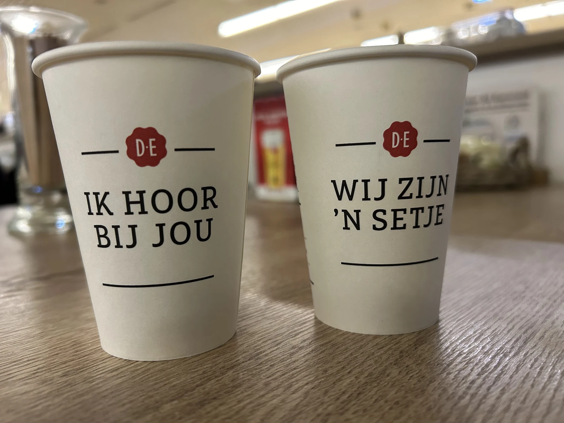Twee witte koffiebekers met Nederlands opschrift 'Ik hoor bij jou' en 'Wij zijn 'n setje'