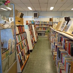 Boekenrekken langs de wanden van een kringloopwinkel met diverse tweedehands boeken