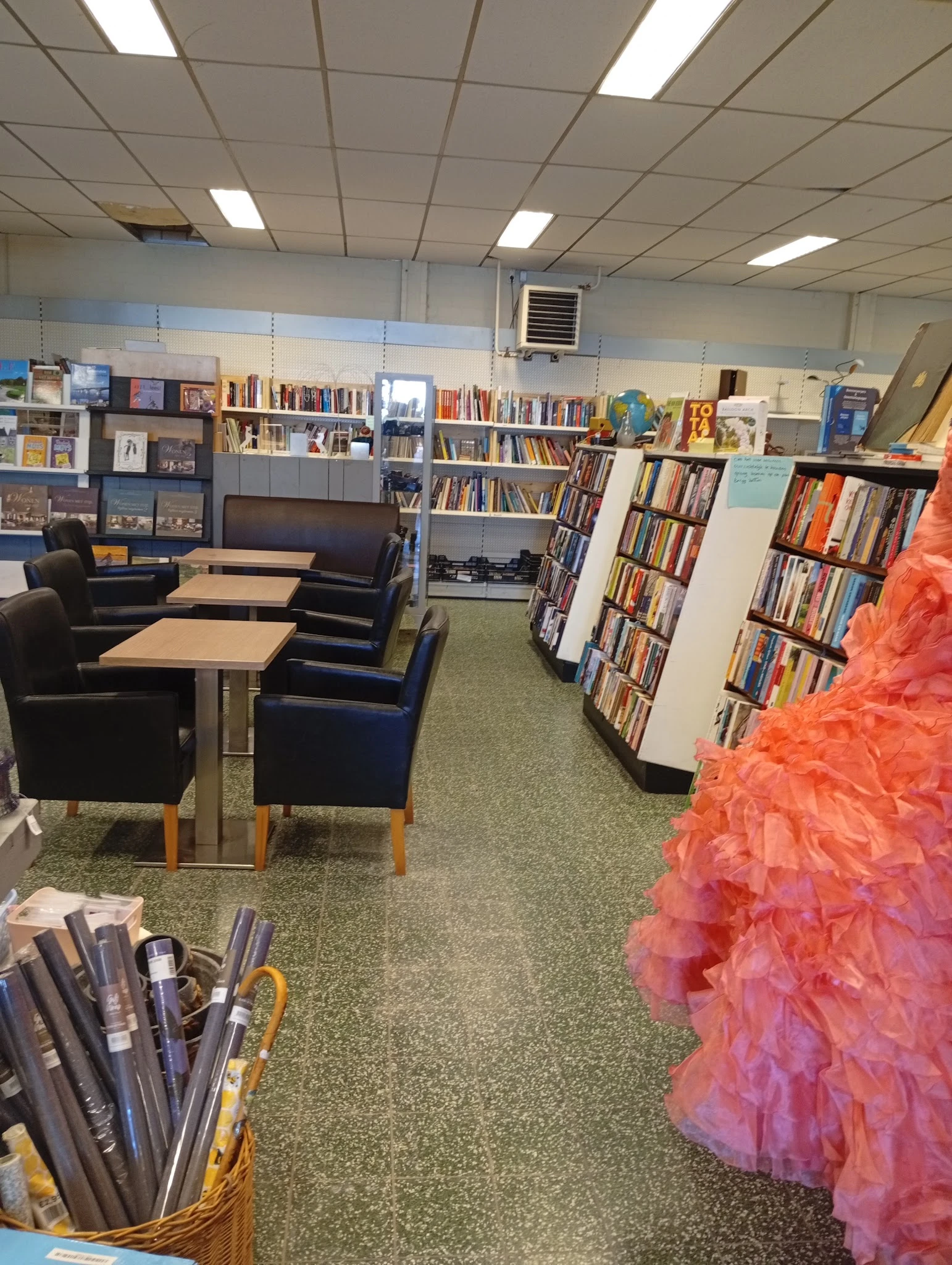 Leeszaal met zwarte fauteuils, tafels en boekenkasten vol met tweedehands boeken en media