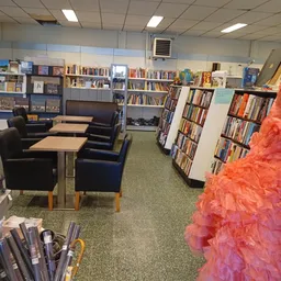 Leeszaal met zwarte fauteuils, tafels en boekenkasten vol met tweedehands boeken en media