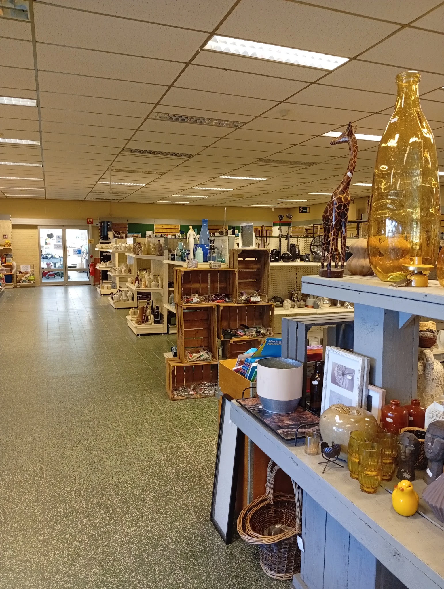 Winkelvloer van kringloopwinkel met diverse gebruikte artikelen, meubels en huishoudspullen uitgestald op tafels en stellinge