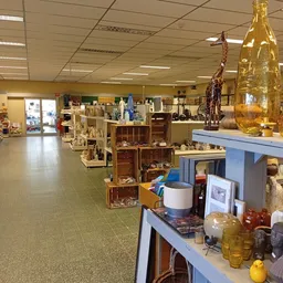 Winkelvloer van kringloopwinkel met diverse gebruikte artikelen, meubels en huishoudspullen uitgestald op tafels en stellinge