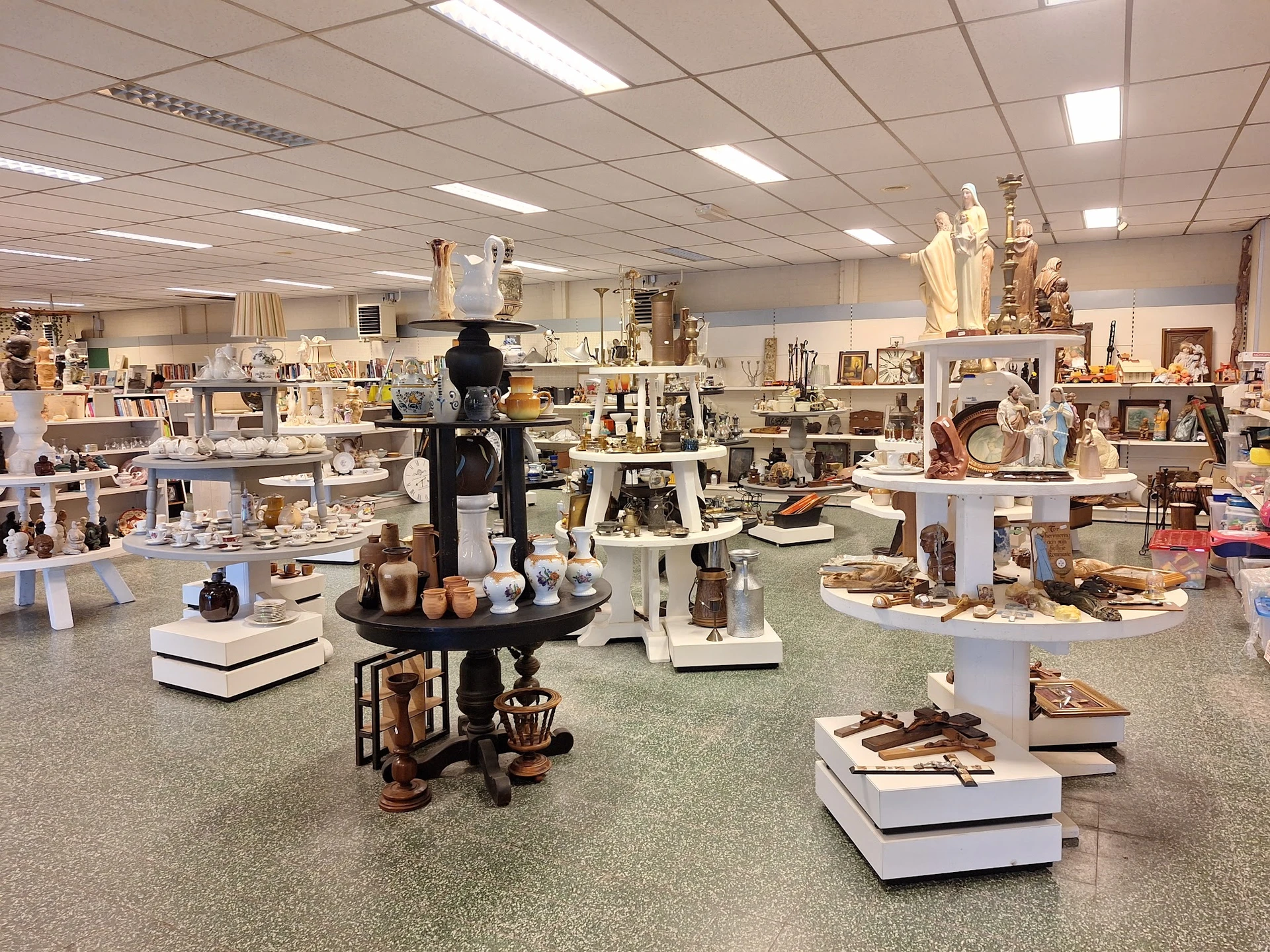 Ruime winkelruimte met vele display-tafels vol decoratieartikelen, beelden en huishoudspullen