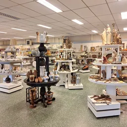 Ruime winkelruimte met vele display-tafels vol decoratieartikelen, beelden en huishoudspullen