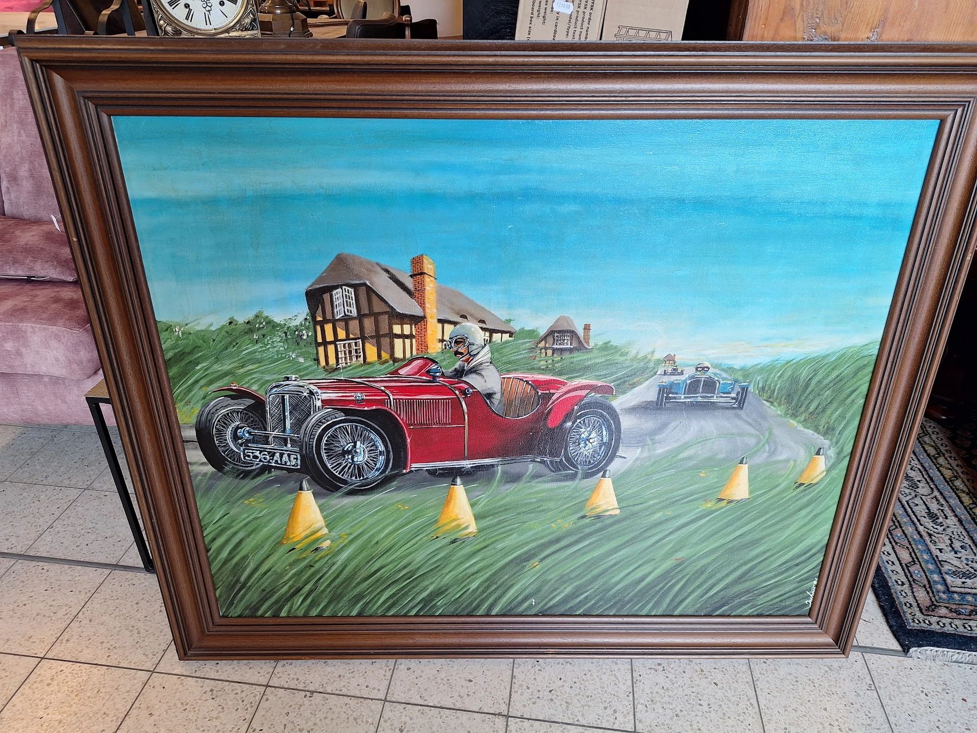 Geschilderd kunstwerk in houten lijst met vintage rode sportwagen op landelijk landschap