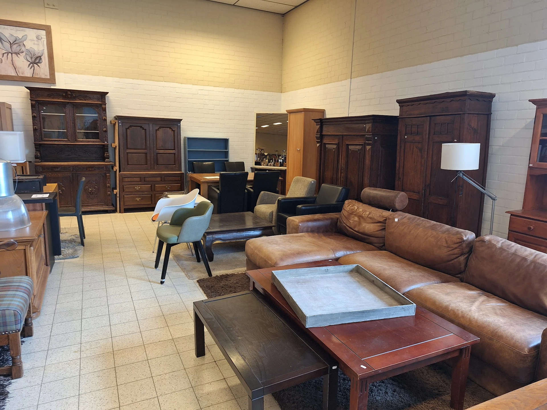 Winkelvloer met bruine lederen meubels, houten kasten en tafels uitgestald in een ruim interieur
