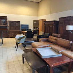 Winkelvloer met bruine lederen meubels, houten kasten en tafels uitgestald in een ruim interieur