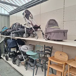 Uitstallingen met kinderartikelen: kinderwagens, buggy's, stoelen en andere babygoederen in de kringloopwinkel