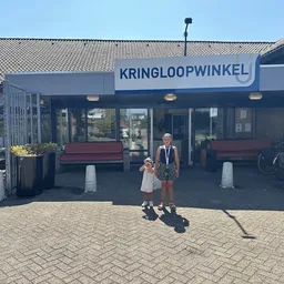 Gevel van kringloopwinkel Verderest met blauwe naam en twee personen ervoor