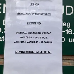 Papier met openingstijden van kringloopwinkel Geopend