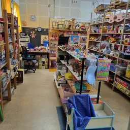 Binnenkant van kringloopwinkel met houten stellingen vol spullen, karren en diverse tweedehands artikelen