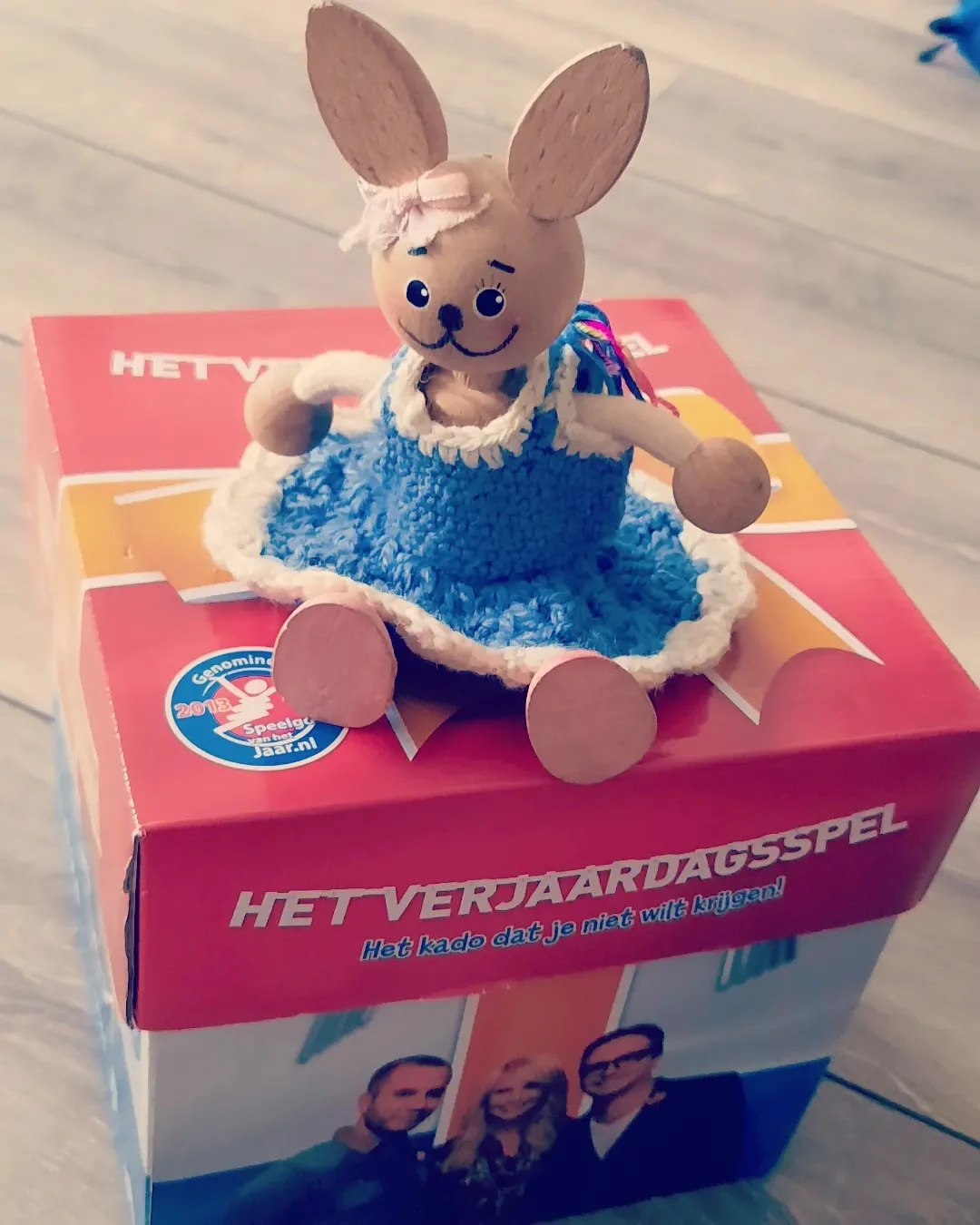 Vintage speelgoed: Een blauwe pluchen pop met wit gezicht op een roze verpakking van 'Het Verjaardagsspel'
