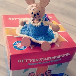 Vintage speelgoed: Een blauwe pluchen pop met wit gezicht op een roze verpakking van 'Het Verjaardagsspel'