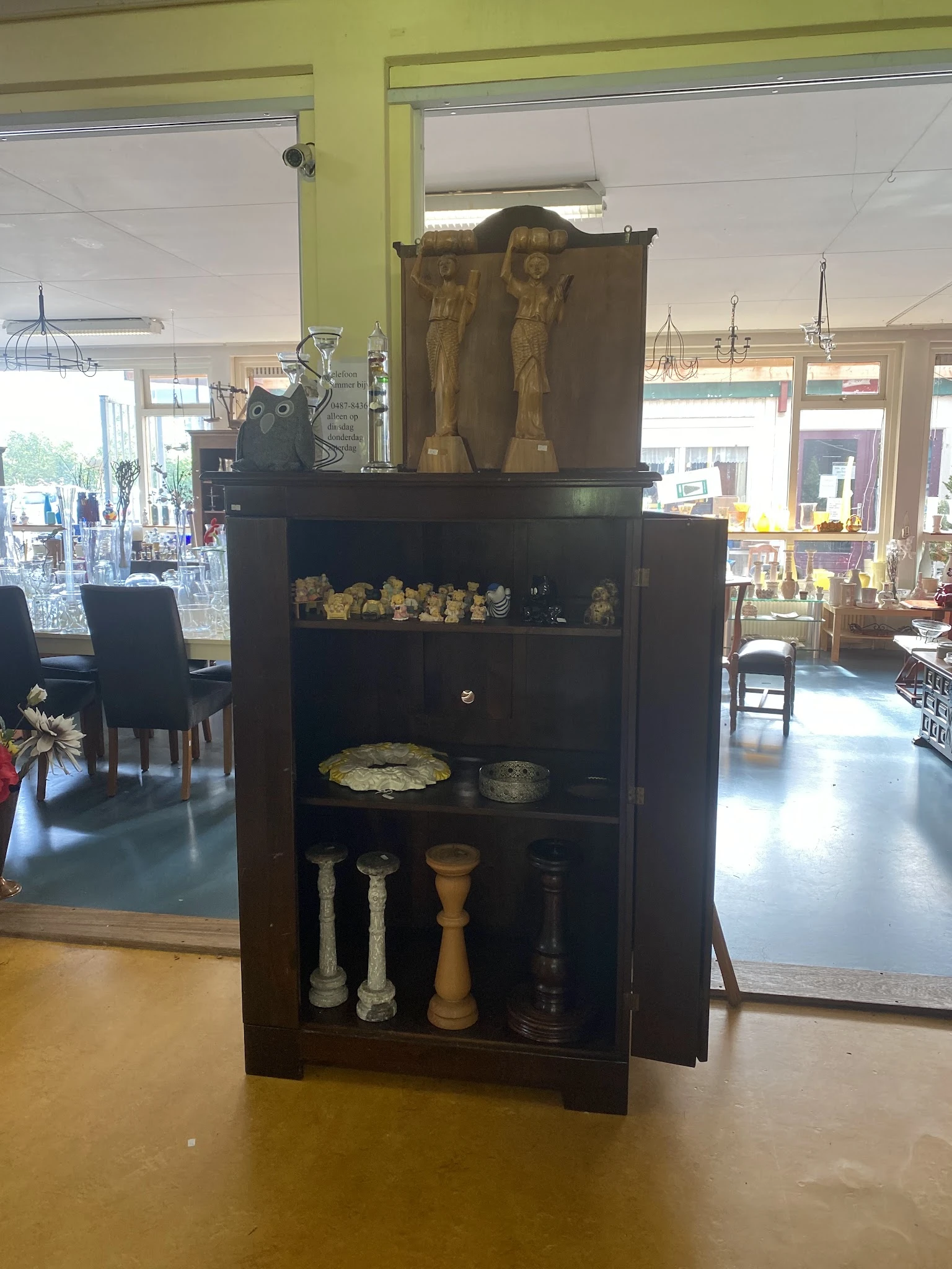 Zwarte vitrinekast met gouden decoratieve beeldjes, schalen en kandelaars op verschillende legels